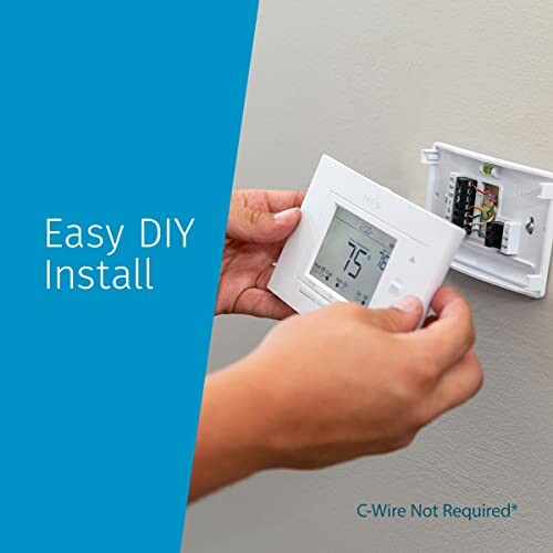 Person installing a digital thermostat on a wall.